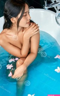 Young Naked Woman Sitting in White Bath with Blue Water Stock Photo