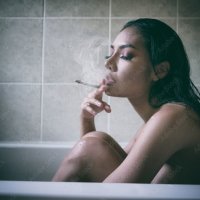 Nude woman smoking cigarette in the bath room Stock Photo