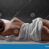 Nude Girl Sleeping with a Gun Under the Pillow Stock Image