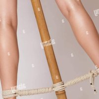 Sexy woman legs tied with bondage ropes to a bamboo pole Stock Photo