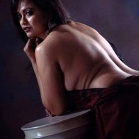 Desi MILF leaning on a half pillar in braless saree and posing topless showing her bare back