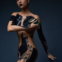 sensual slim young naked woman standing in dark studio and paint black color. Andrey Guryanov