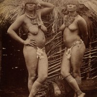 South Africa: Zulu women bare-chested and wearing ornamental jewellery posing outside a mud hut. Photograph 18801890.