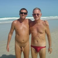 File:Two men on the beach one wearing swimtrunks the other nude.jpg